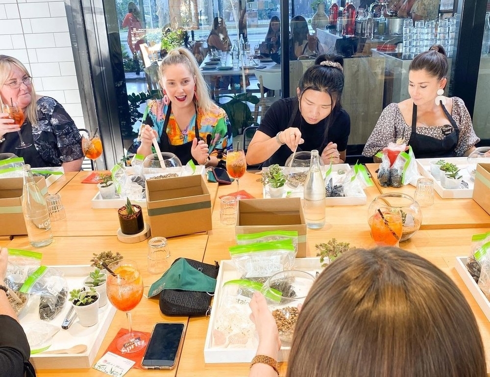 Friends potting tiny succulents into glass terrariums around the workshop table