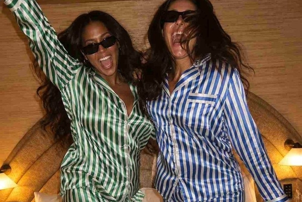 Two friends in striped pyjamas dancing with their arms in the air