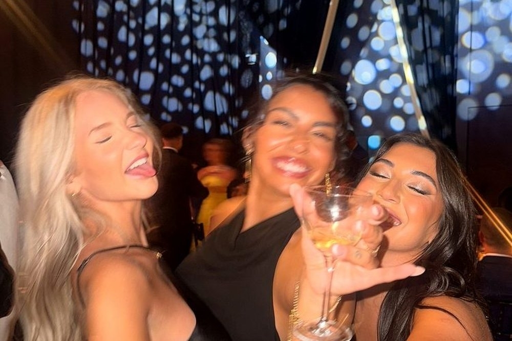 Three friends cheering their glasses toward the camera in the nightclub