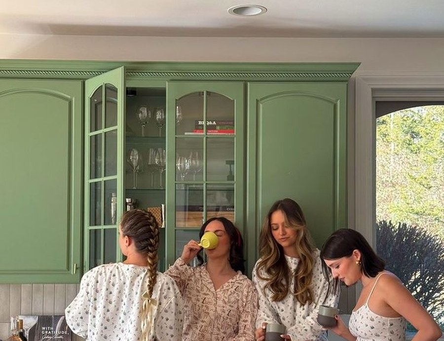Four friends in pyjamas sipping coffee in the kitchen the next morning