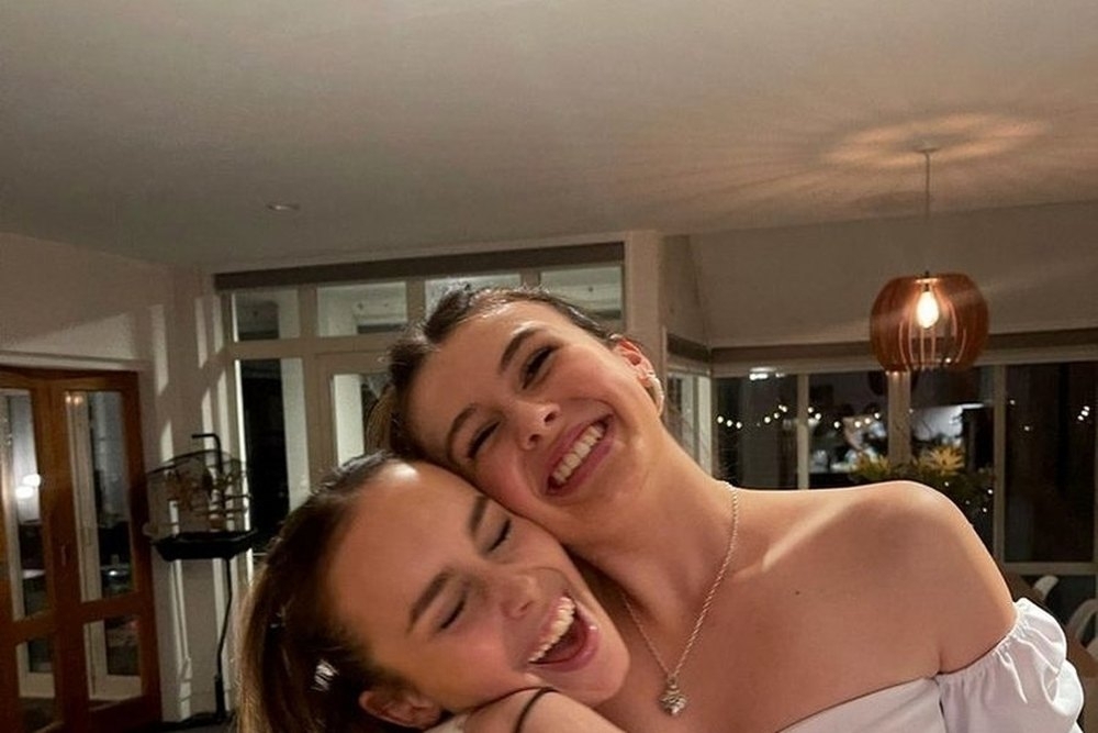 Two friends cheek to cheek laughing in the living room