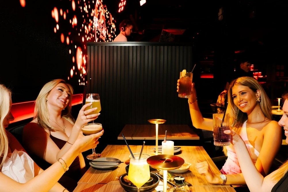 Friends raising their drinks at a dimly lit restaurant table