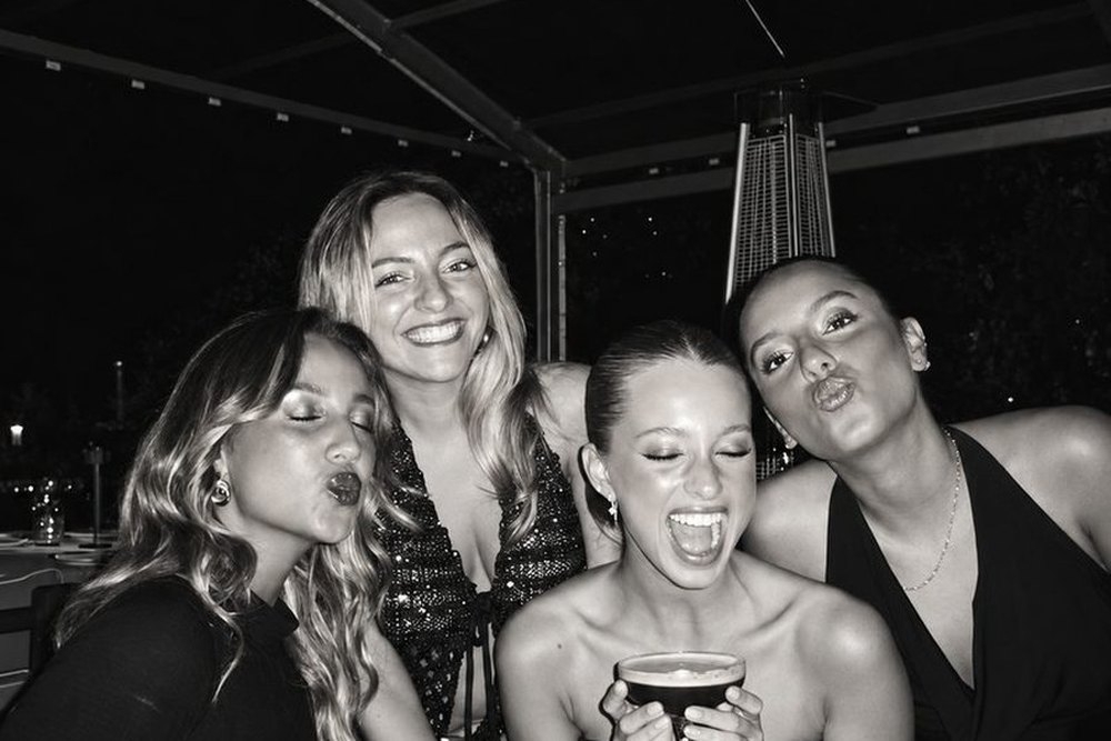 Black and white shot of four friends laughing and pouting on a night out