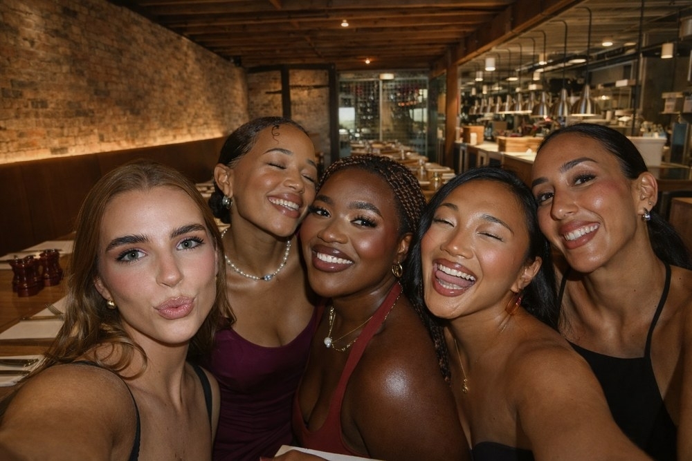 Five friends squeezed in for a selfie at a candlelit dinner
