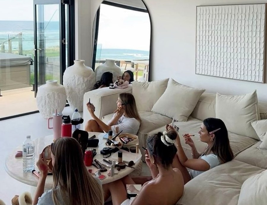 Friends doing their makeup together on the apartment couches before dinner