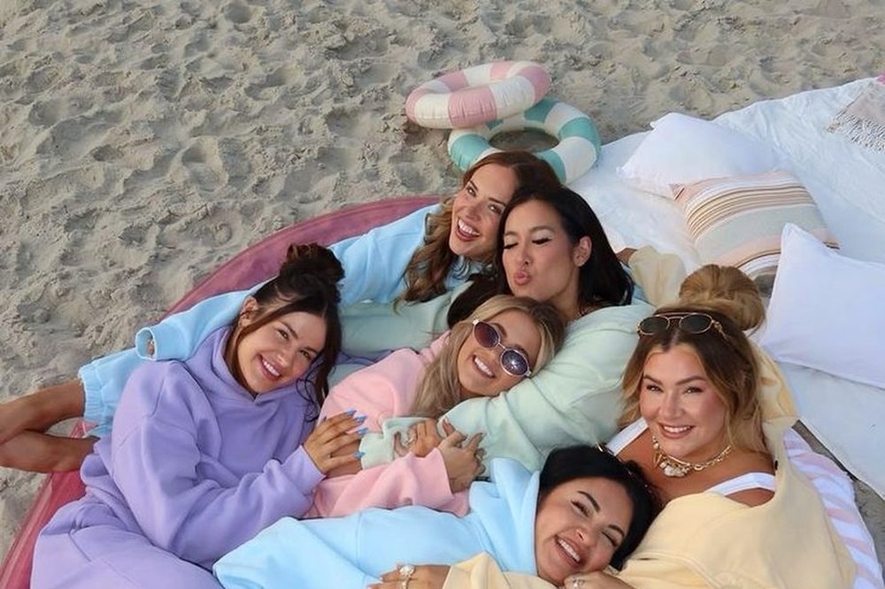 Six friends in pastel hoodies piled onto a quad bike
