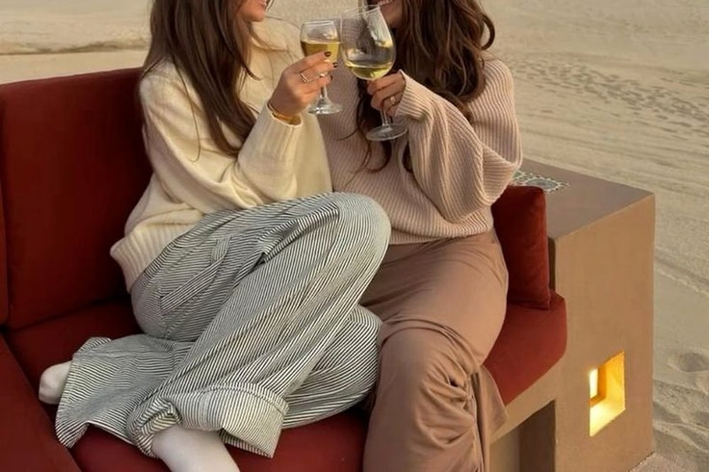 Two friends toasting on a beachside lounge as the sun goes down