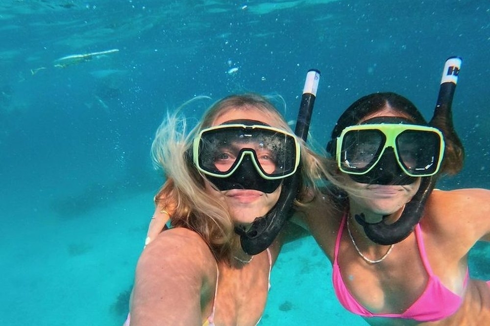 Two friends in snorkel masks grinning in clear blue water