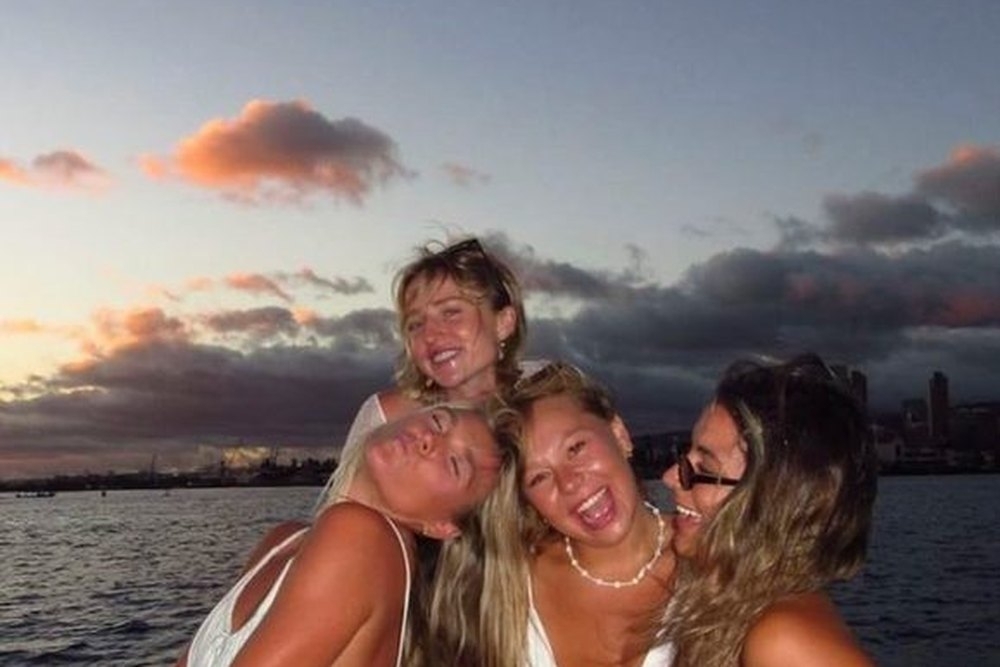Four friends laughing together on the boat back at dusk