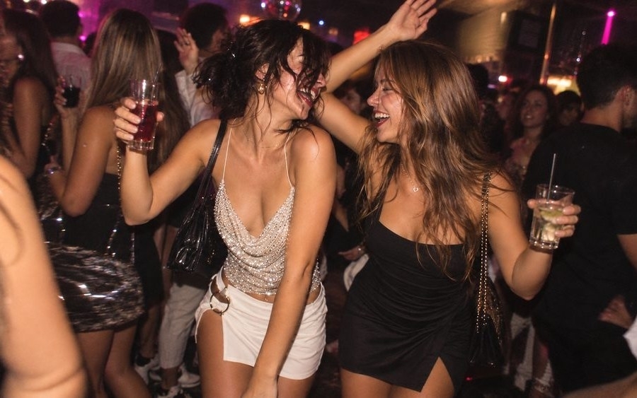 The girls dancing with drinks in hand on a packed nightclub dance floor