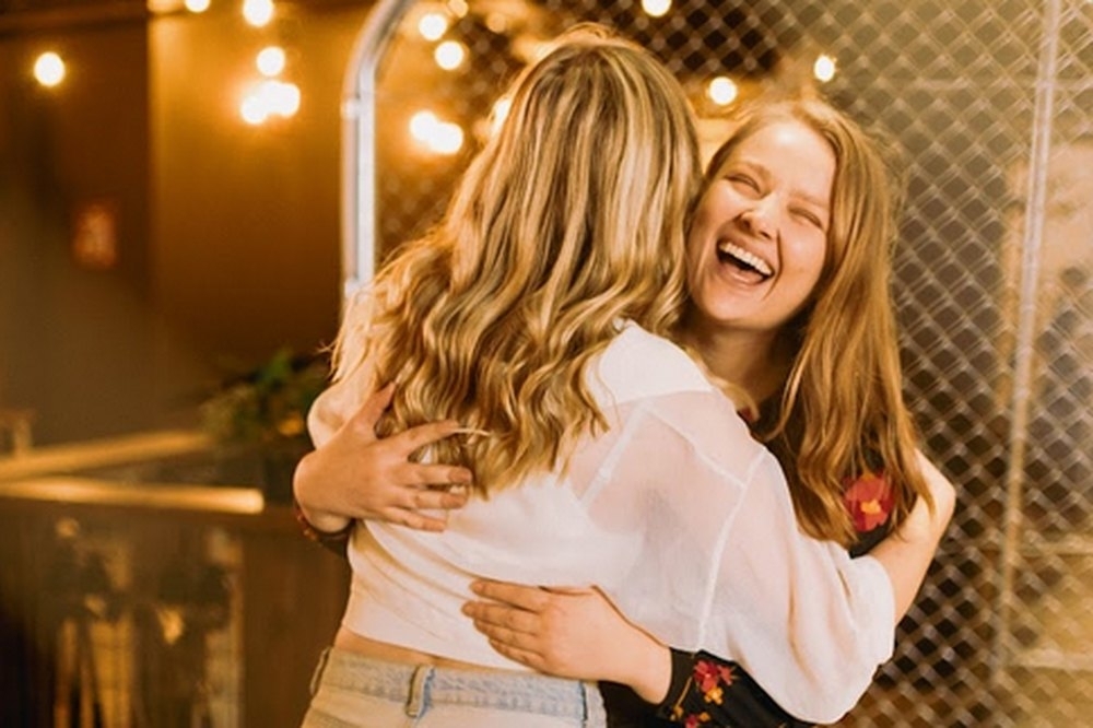 Two friends hugging and laughing between throws at the axe throwing lanes