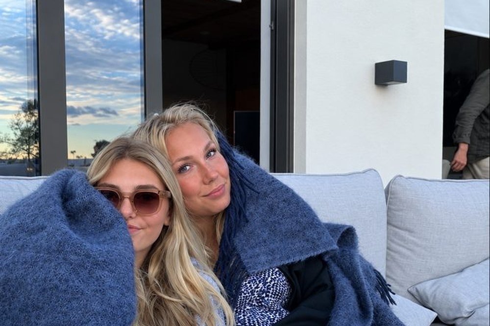 Two friends wrapped in a blanket relaxing on a daybed
