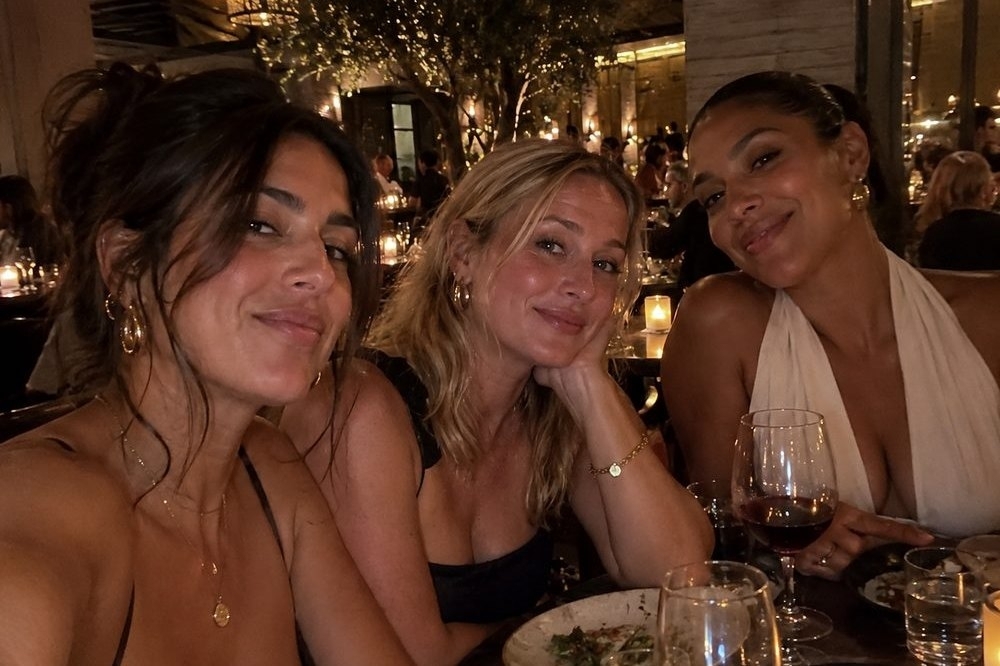 Three friends leaning in for a selfie over dinner