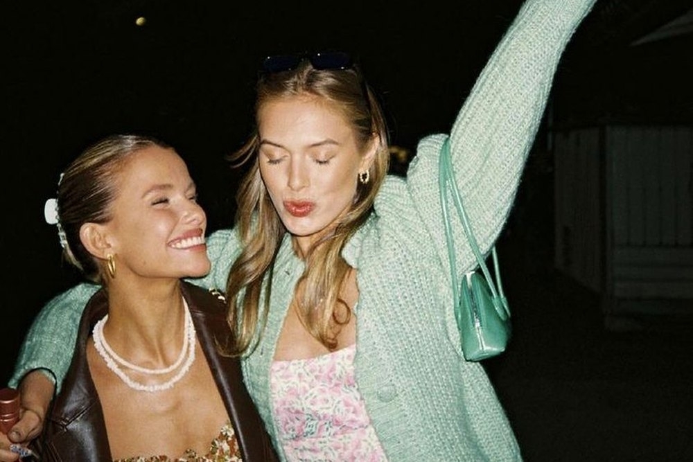 Two friends laughing with an arm in the air on a night out