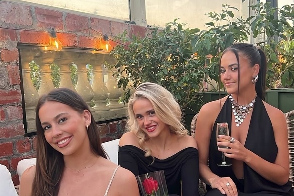 Friends laughing with drinks on a leafy rooftop terrace in the evening light