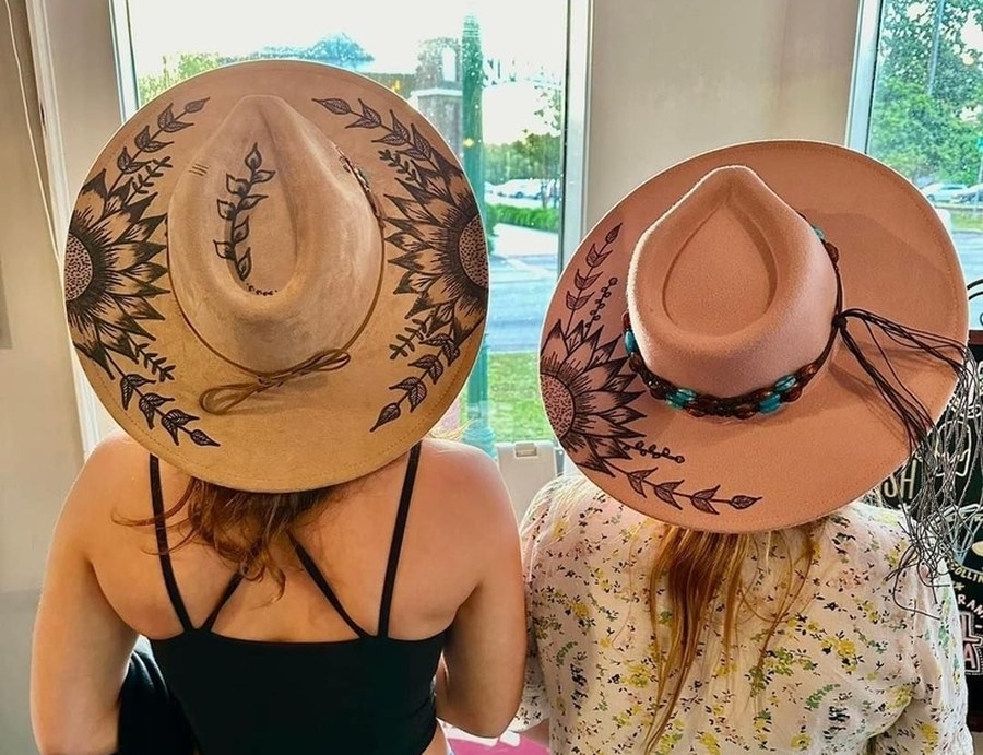 Two friends showing off the designs burned into their felt hats