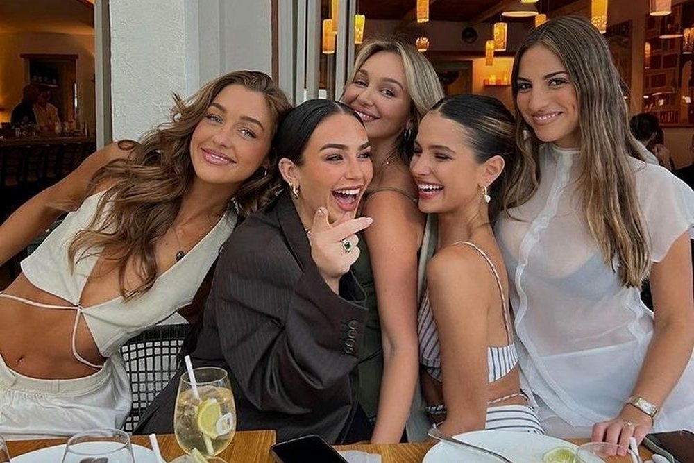 Five friends squeezed together laughing at the dinner table
