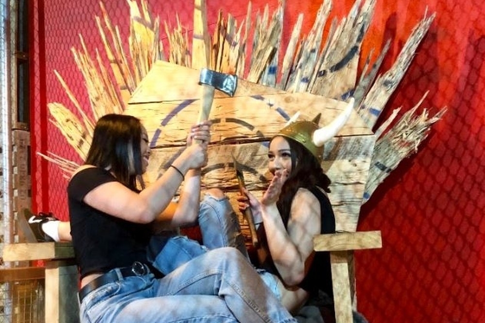 Two friends clowning around on a timber throne, one holding an axe