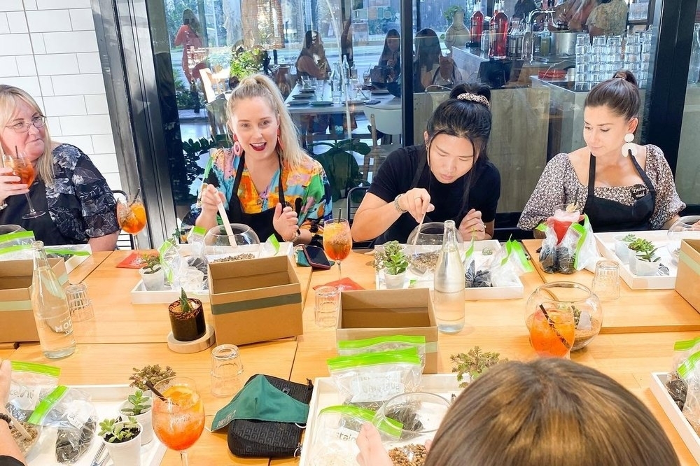 Friends in aprons building terrariums along a long table