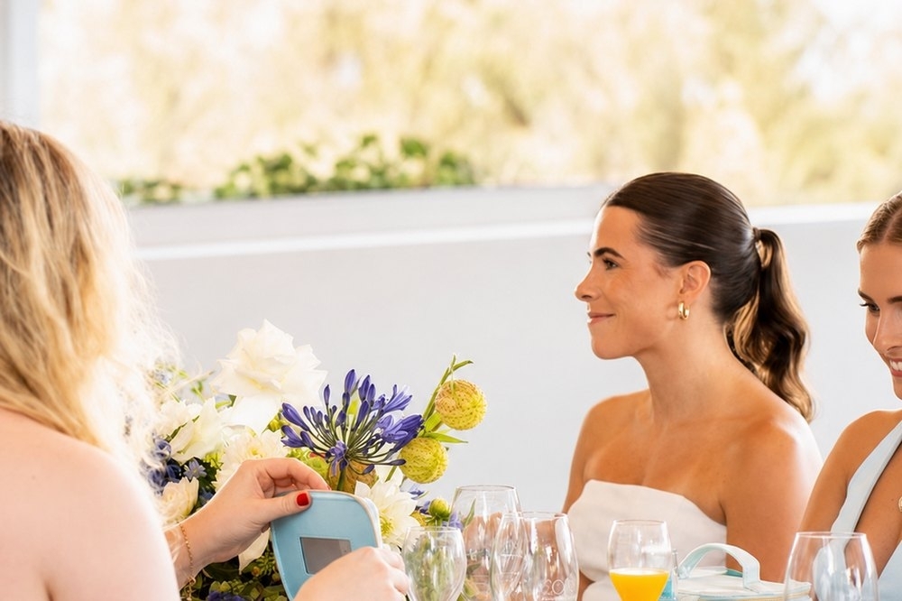 Friends chatting over a long lunch table with flowers and mimosas