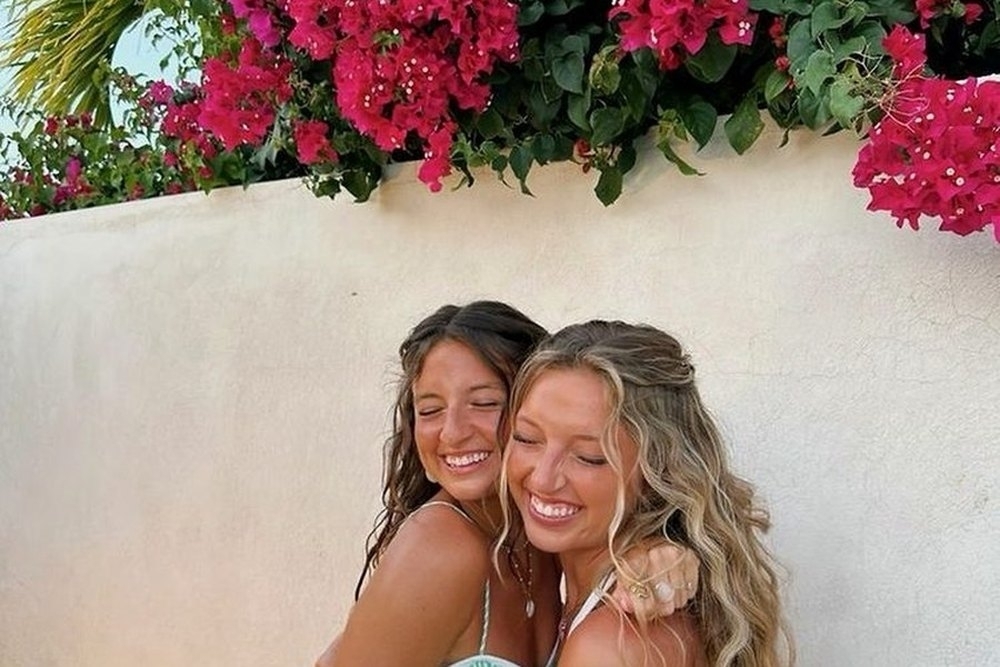 Two friends cheek to cheek under bright bougainvillea