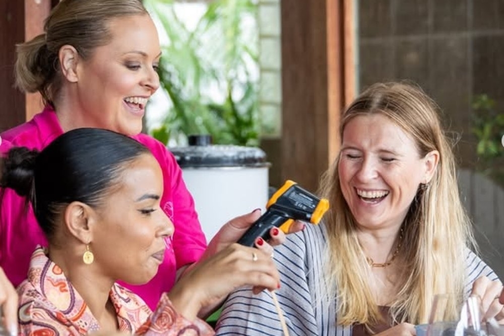 Friends laughing as they pour and test hot wax at a candle making workshop