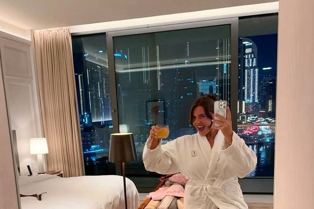 Two friends in robes toasting in the mirror while getting ready