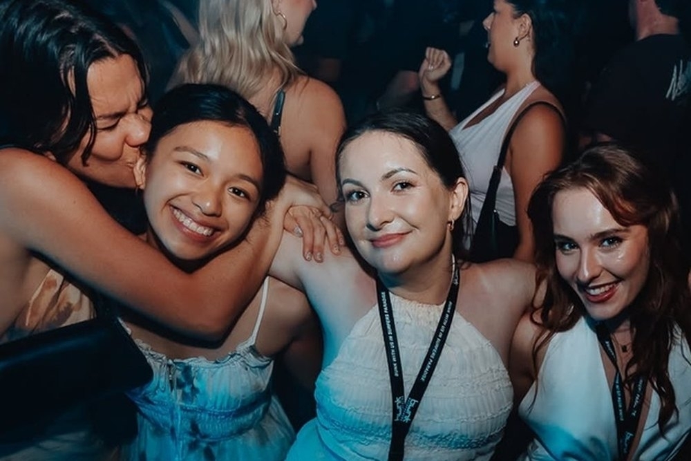 Friends hugging and grinning in a packed nightclub
