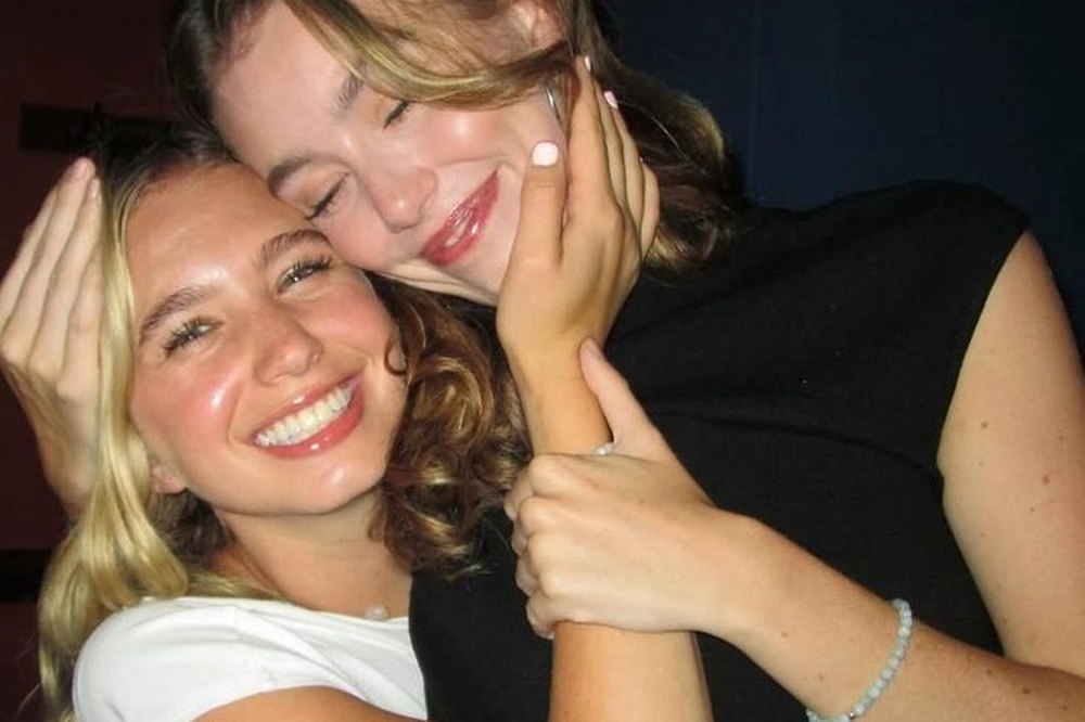 Two friends hugging cheek to cheek at the end of a big night out