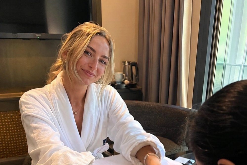 A friend in a robe smiling through her manicure in the apartment
