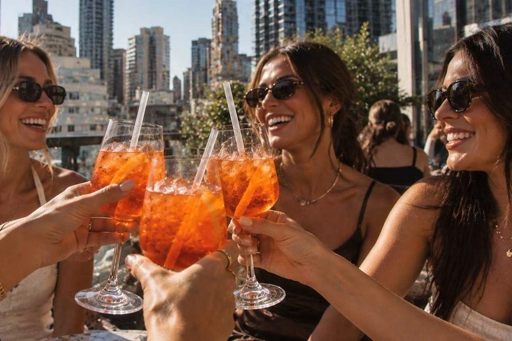 Friends in sunglasses clinking drinks on a rooftop