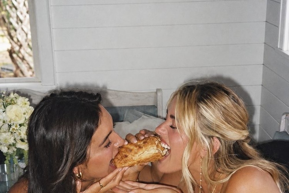Two friends biting into the same sweet treat at home