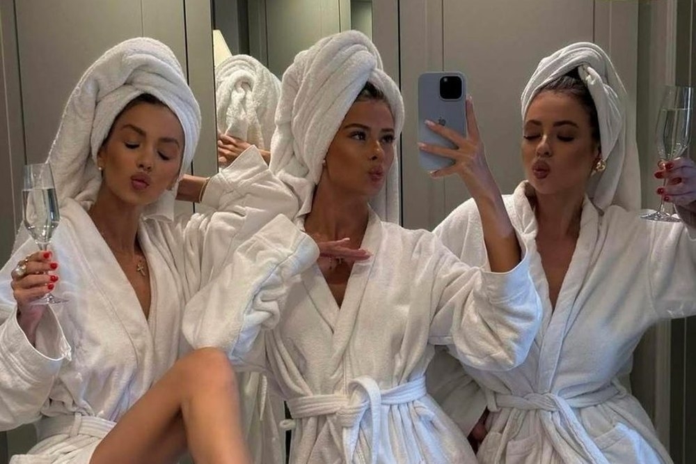 Three friends in robes and towel turbans taking a mirror selfie while getting ready